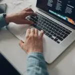 person wearing long-sleeve top working on laptop